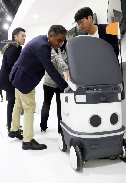 KT 부스를 찾은 관람객들이 자율주행이 가능한 실외 배송로봇(Delivery Robot)을 살펴보고 있다. 뉴스1
