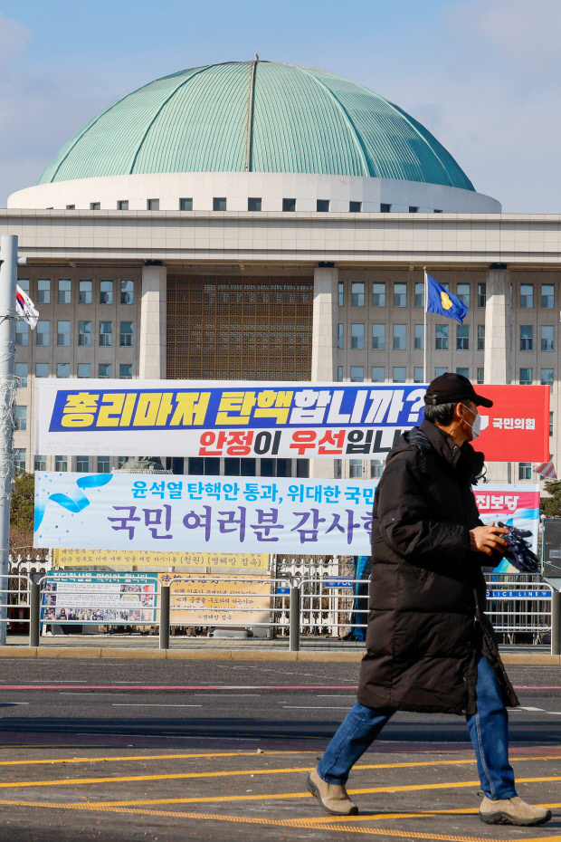 한덕수 대통령 권한대행에 대한 즉각적인 탄핵 절차에 나서려던 더불어민주당이 잠시 숨 고르기에 들어간 지난 25일 서울 여의도 국회의사당 앞에 국민의힘과 진보당이 내건 현수막이 걸려 있다. 뉴스1